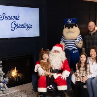 Little girl dressed as a reindeer on Santa's lap with family